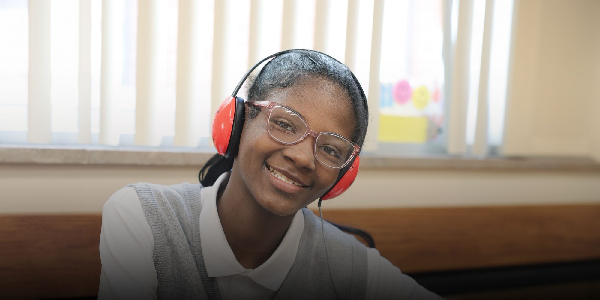 Smiling student sitting at desk wearing headphones